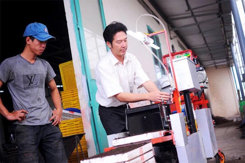 Anh Nguyễn Hồng Chương (phải) điều chỉnh chiếc máy gieo hạt chân không “6 trong 1” tự động của mình - Ảnh: Lâm Thiên